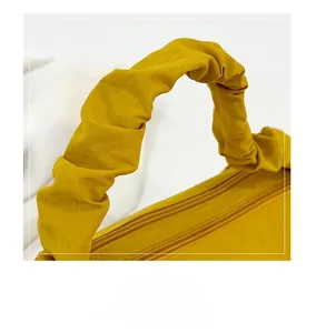 Detail view of bright yellow nylon handbag with ruffled handle and double metal zippers