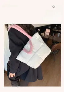 Close-up of a white quilted puffer tote bag with contrasting pink padded handles