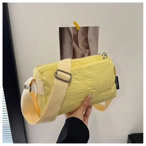 Detail view of yellow nylon crossbody bag featuring multi-layer zippers and adjustable strap