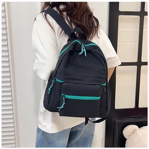 Close-up of black backpack featuring vibrant turquoise zippers and functional pockets