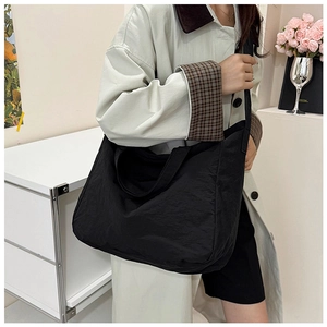 Detail showing the pleated texture and wide shoulder strap of a large black tote bag