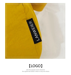 Detailed macro view of yellow nylon handbag featuring a black woven brand logo label