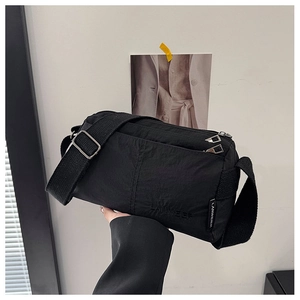 Detail of black nylon crossbody bag with adjustable wide strap and multi-pocket design