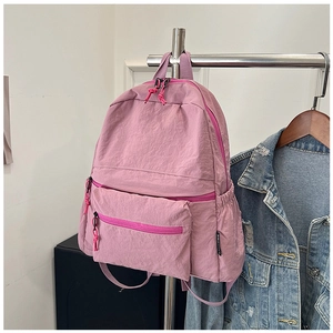 Detailed view of pink nylon backpack hanging with denim jacket in a daily casual setting