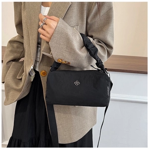Detail of minimalist black nylon crossbody bag with ruffled handle and silver metal logo