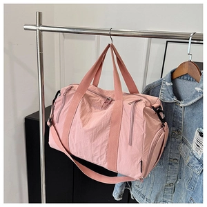 Detail of pink nylon duffel bag featuring side zipper pocket and woven shoulder strap