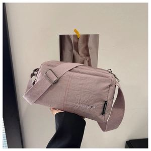 Detail of dusty pink textured nylon crossbody bag with LANWEIER embroidery and wide strap