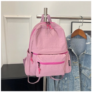 Detail view of pink nylon backpack with side brand label and stylish knotted zippers