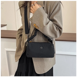 Detail of black nylon shoulder bag featuring ruffled handles and adjustable wide strap