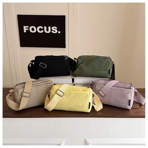 Detail view of five assorted nylon crossbody bags with adjustable straps in a studio setting