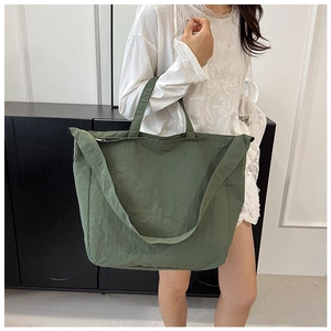 Detail view of the olive green canvas tote bag with metal zipper and crossbody strap