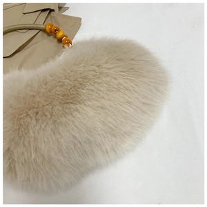 Détail du sac à main en fausse fourrure beige avec poignée élégante en perles d'ambre