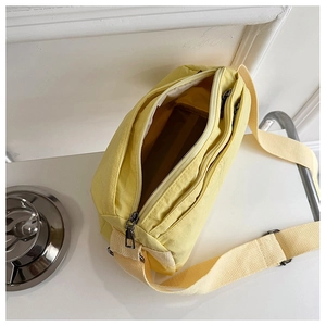 Detail view of large capacity yellow crossbody bag showing compartments and zippers