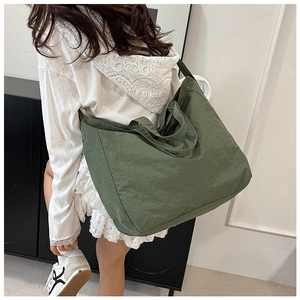 Detail view of large army green canvas tote bag showing its texture and capacity on model