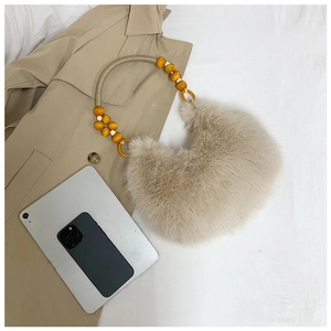 Détail du sac croissant en peluche beige avec poignée décorative en perles de bois naturel