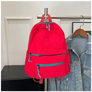 Detail view of red casual backpack with durable fabric and blue accent zipper cords