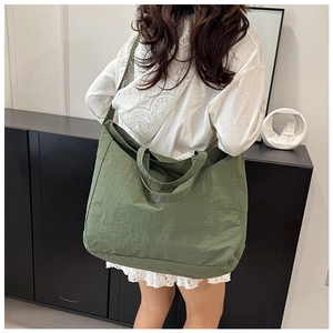 Army green large canvas tote bag with shoulder strap shown in a lifestyle model shot