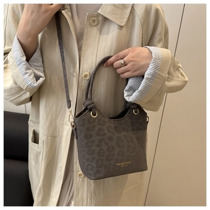 Detailed view of leopard print bucket bag with gold hardware and logo on faux suede material