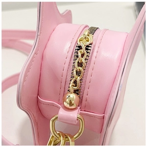 Macro shot of gold zipper closure and ball pendant on pink leather star shape bag