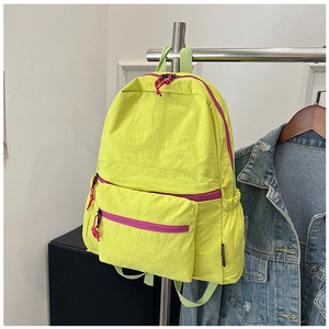 Detail of neon yellow nylon backpack featuring bright pink zippers and spacious front pocket