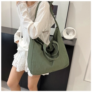 Green canvas tote bag with adjustable strap shown in a minimalist home setting