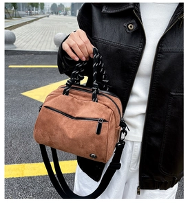 Detail of caramel brown suede crossbody bag with striped woven handle and metal logo