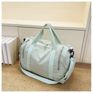 Detail view of mint green nylon gym bag with adjustable shoulder strap and zippers