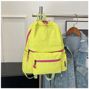 Detail view of neon yellow lightweight backpack with contrast rose red zippers