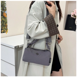 Detail of grey nylon crossbody bag featuring a flower logo and cloud-style ruffled strap