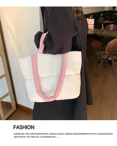 Close-up of quilted cream tote bag with pink puffer straps in a cafe setting