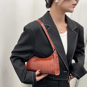 Brown crocodile pattern faux leather shoulder bag worn as a stylish underarm baguette