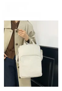 Dettaglio di una grande borsa a tracolla in tessuto oxford crema indossata da una modella