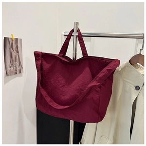 Detail view of burgundy large capacity tote bag hanging with stylish wide strap