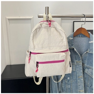 Detail view of beige nylon backpack with vibrant magenta zippers and front pocket