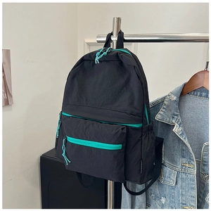 Detailed view of the black nylon backpack featuring vibrant turquoise zipper accents