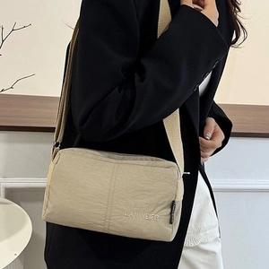 Minimalist beige crossbody bag with embroidered logo and wide adjustable strap