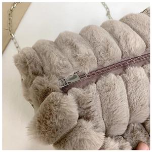 Détail du sac à main en peluche avec matelassage rayé et bandoulière chaîne argentée