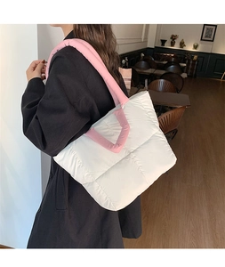 Quilted tote bag detail featuring white body and pink padded straps in a cafe setting