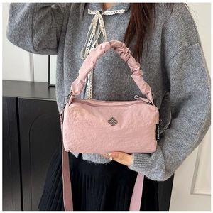 Detailed view of pink nylon handbag with ruffled handle and silver flower emblem