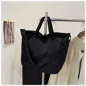 Close-up detail of a black large capacity tote bag with wide shoulder strap on a hanger