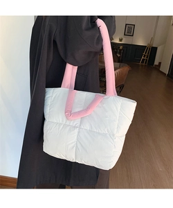 Quilted white puffer tote bag with pink handles worn by a model in a cozy indoor setting