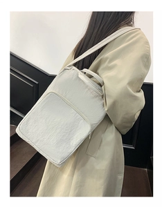 Dettaglio della borsa tote in oxford crema con ampia tasca frontale e tracolle resistenti