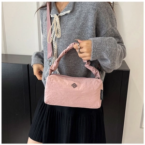 Pink nylon handbag detail with floral metal logo and adjustable wide strap on model