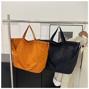 Detail of large canvas tote bags in orange and black with wide shoulder straps