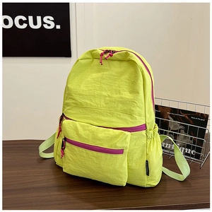 Detail of neon green nylon backpack showing side pocket and purple zipper trim
