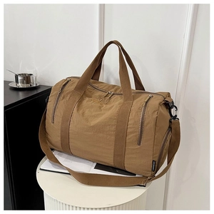 Detail view of brown nylon travel bag featuring reinforced handles and adjustable strap