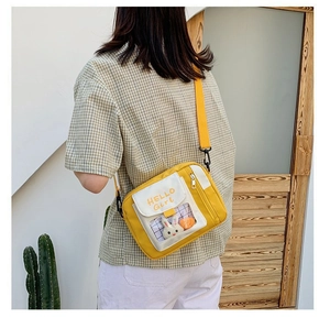 Détail d'un sac à bandoulière en toile jaune avec texte HELLO Girl et peluche lapin blanc