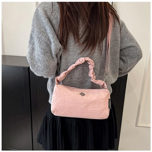 Detailed close-up of light pink nylon handbag with ruched handles and adjustable strap