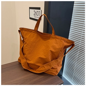 Detail view of large orange canvas tote bag with unique crinkled fabric and wide strap