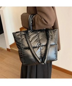 Side view of a large black padded tote bag showing the glossy quilted texture and size scale